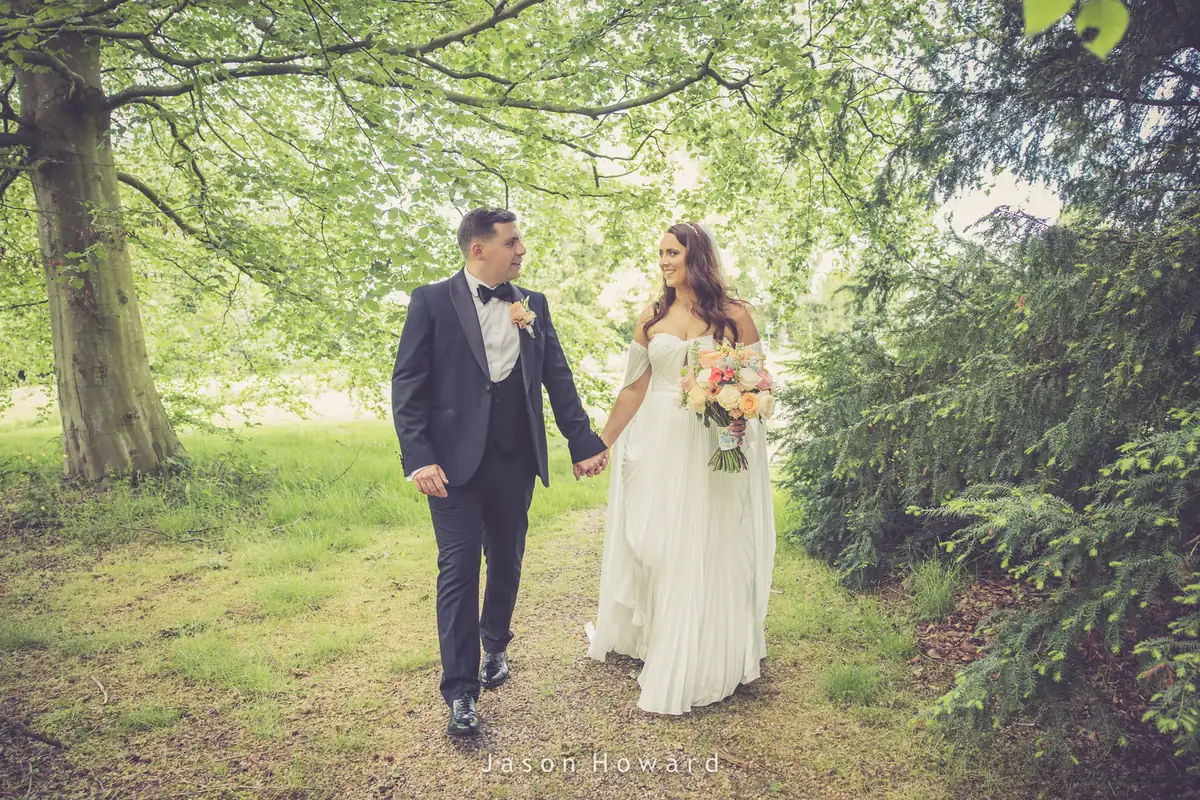 Bride and groom walking through the trees at Rowton Hall Hotel, Chester