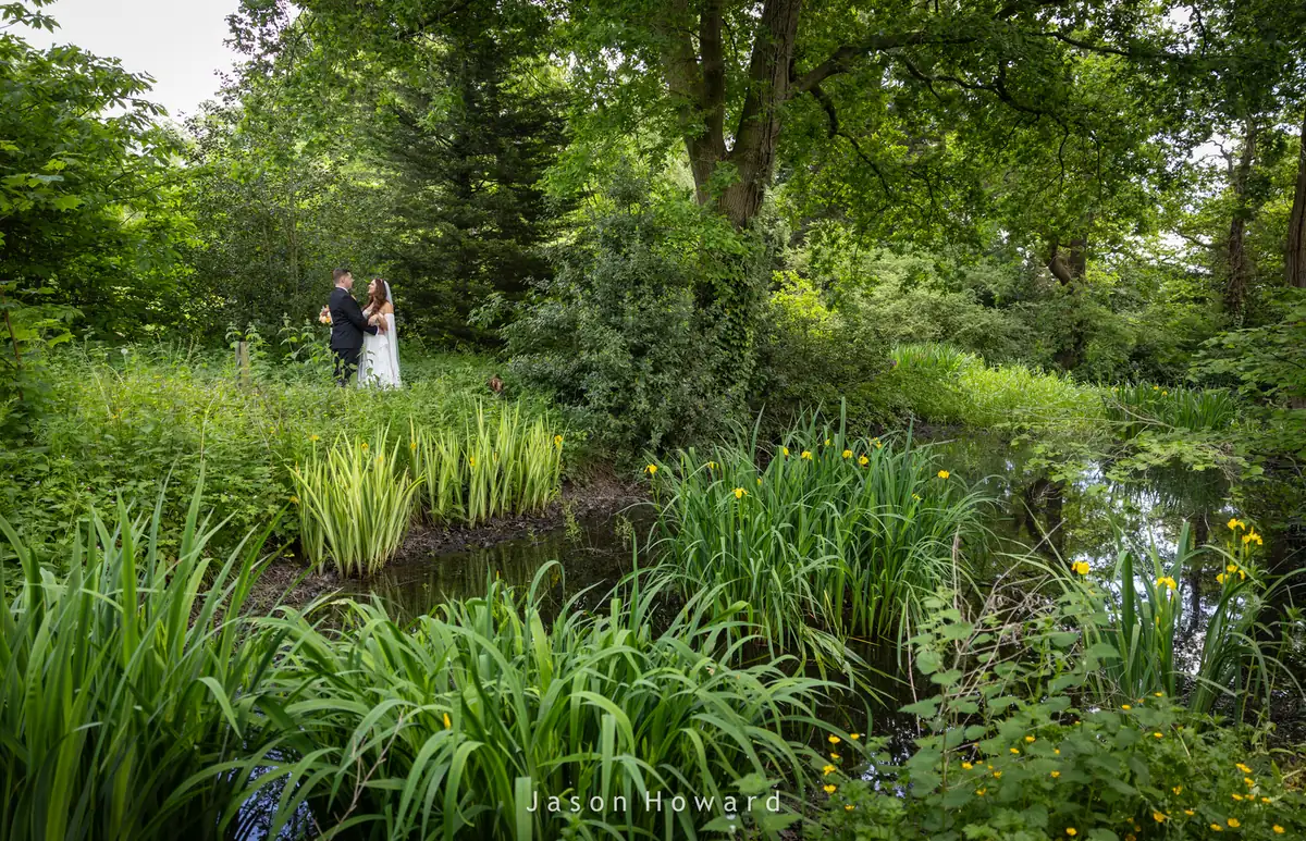 Bride and groom by the pond at Rowton Hall Hotel, Chester