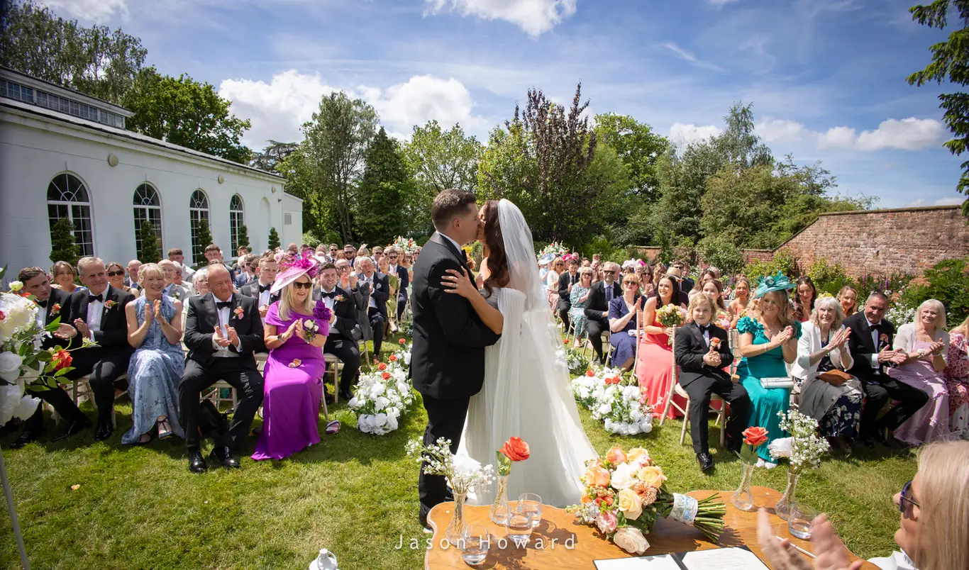 First kiss in the gardens at a Rowton Hall Hotel wedding