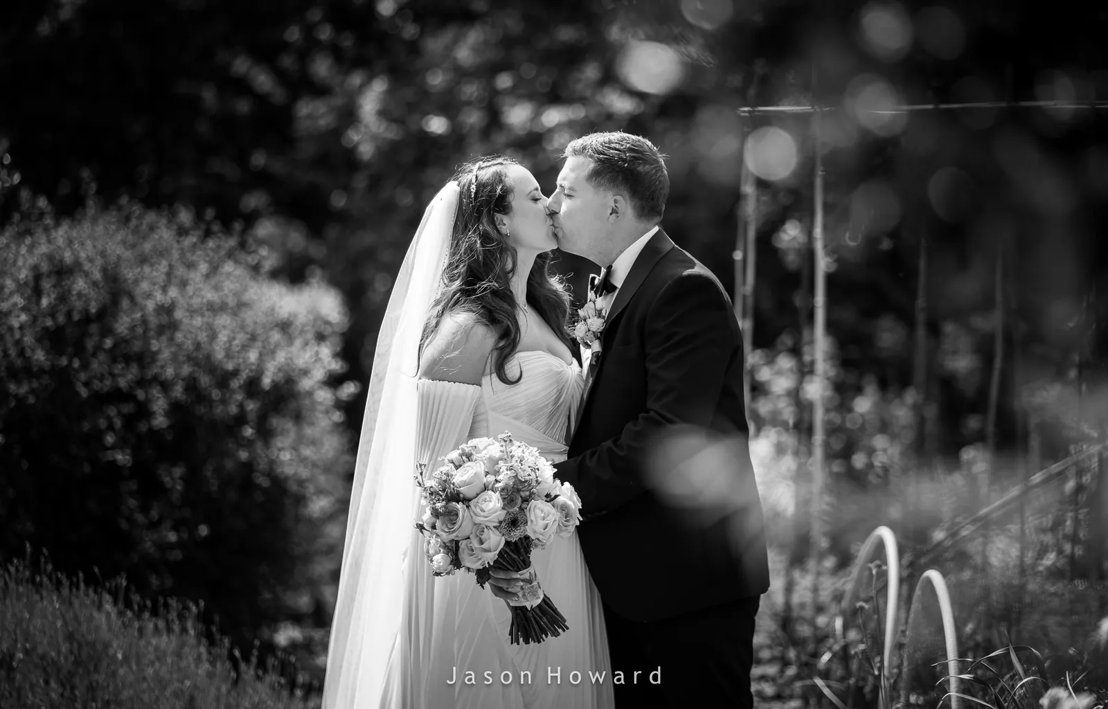 Bride and groom kiss in the garden at Rowton Hall Hotel, Chester