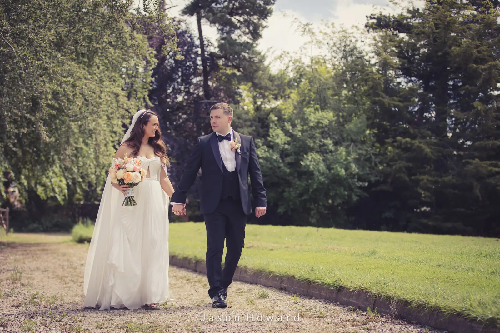 Newlyweds walking through the gardens at Rowton Hall Hotel, Cheshire